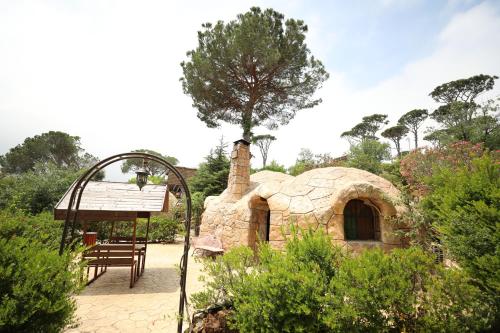 a small stone house in the middle of a garden at Pineland Hotel and Health Resort in Ḩammānā