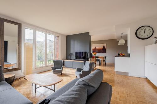 - un salon avec un canapé, des chaises et un réveil dans l'établissement Veeve - Grand in Grey, à Paris