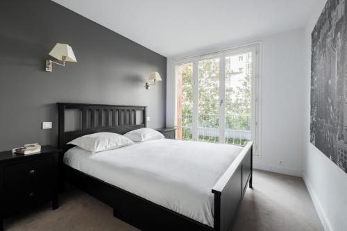 une chambre avec un grand lit et une fenêtre dans l'établissement Veeve - Grand in Grey, à Paris