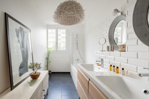 une salle de bain blanche avec un lavabo et un miroir dans l'établissement Veeve - Grand in Grey, à Paris