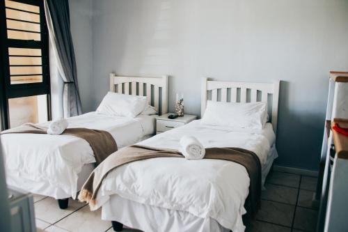 two beds in a room with white sheets and towels at Laaiplek Hotel in Velddrif