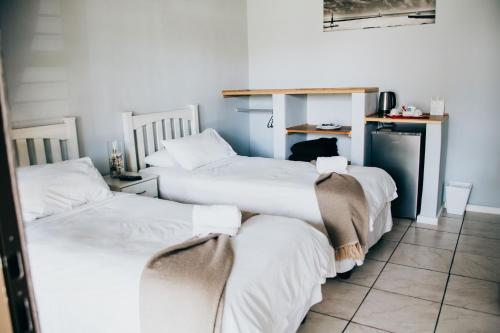 a room with three beds with white sheets at Laaiplek Hotel in Velddrif