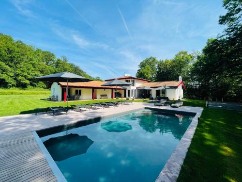 une piscine avec des chaises et une maison dans l'établissement Villa Paulen Pausa, à Uhart-Cize