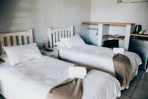 two beds in a room with white sheets at Laaiplek Hotel in Velddrif
