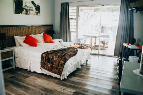 a bedroom with a bed with white sheets and orange pillows at Laaiplek Hotel in Velddrif