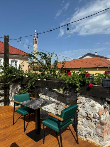 un patio con mesa, sillas y pared de piedra. en Hotel Ikona, en Shkodër