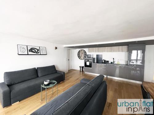 un salon avec un canapé noir et une cuisine dans l'établissement Urban Flat 89 - Charming 3 Bedroom Flat in Paris, à Paris