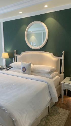 a bedroom with a large white bed with a mirror at Welcomhotel by ITC Hotels, The Savoy, Mussoorie in Mussoorie