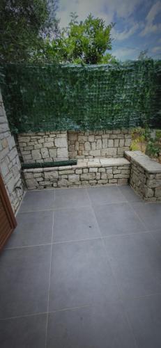 a patio with a stone wall and a stone bench at Eglent's tourist house in Sarandë