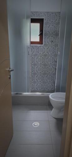 a bathroom with a toilet and a shower with a window at Eglent's tourist house in Sarandë