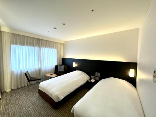 a hotel room with two beds and a window at Spa World HOTEL&RESORT in Osaka