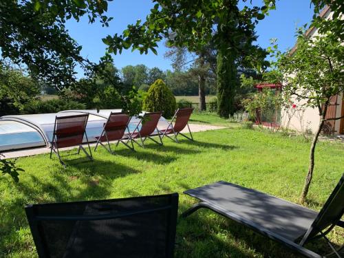 un groupe de chaises assises dans l'herbe dans une cour dans l'établissement Gîte 3 étoiles les Gourlines avec balneo, véranda, piscine et garage, à Avermes