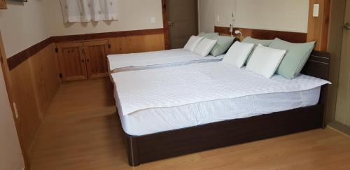 a bedroom with two beds with white sheets and green pillows at Starlight Rest Area in Jeonju