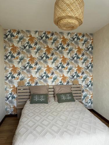 Un dormitorio con una cama grande con una pared floral. en Appartement 35 m2 1er étage 200 m de la mer avec jardin, en Luc-sur-Mer
