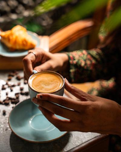 a person holding a cup of coffee on a table at Arnna-Goregaon in Mumbai