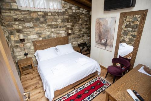 a bedroom with a white bed and a stone wall at Vista Boutique Hotel in Berat