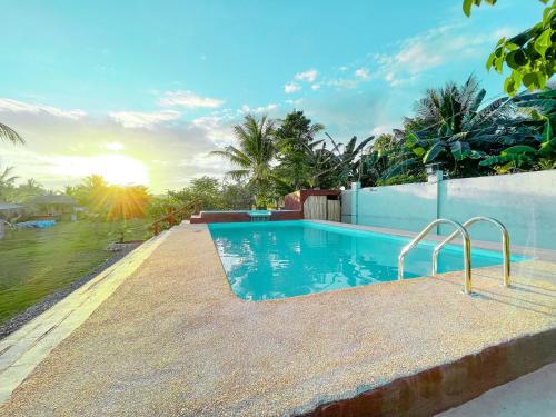 a swimming pool in a villa with the sun setting at Noah's Ark Hotel powered by Cocotel in Dauis