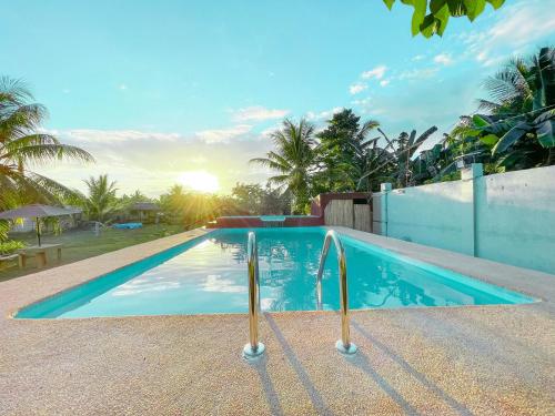 a swimming pool in a resort with the sun setting at Noah's Ark Hotel powered by Cocotel in Dauis