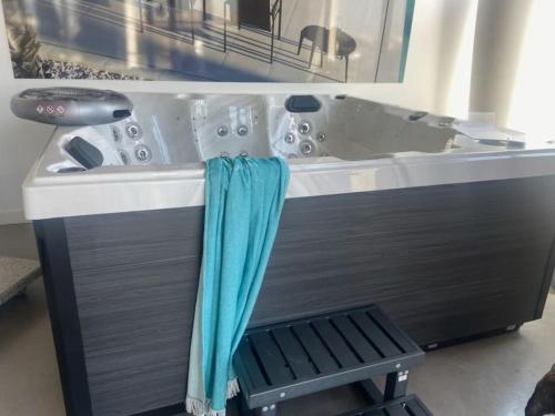 La salle de bains est pourvue d'une baignoire et d'une serviette bleue. dans l'établissement Maison pour 4, Mer et marais salants, Spa, à Guérande