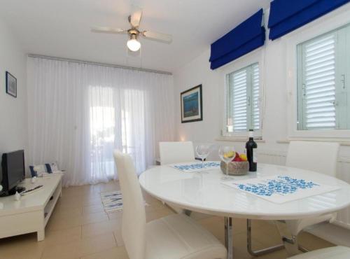 a white dining room with a white table and chairs at Apartments Villa Olea in Lumbarda
