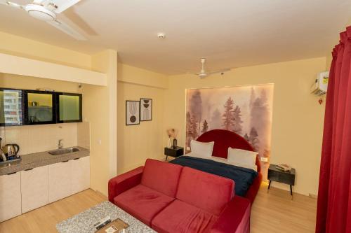 a living room with a red couch and a kitchen at Skystay Lucknow in Lucknow