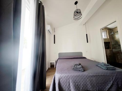 a bedroom with a bed with a purple blanket and a window at Suite IKEBANA Porto Pino in Porto Pino