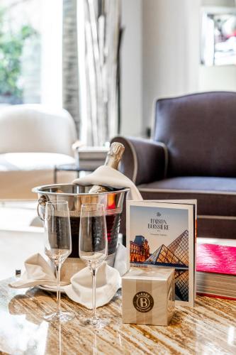 a table with two wine glasses and a box at Maison Boissière BARNES Residences in Paris