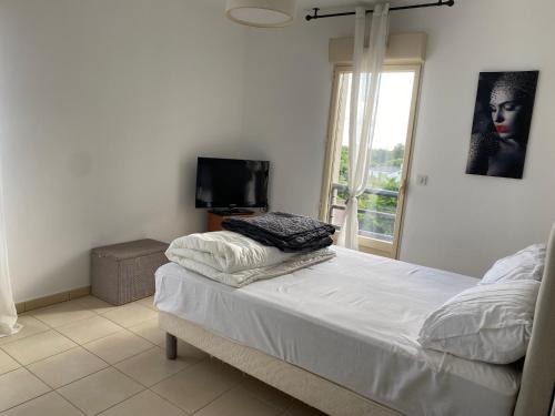 - une chambre avec un lit, une télévision et une fenêtre dans l'établissement Superbe appartement avec parking privé, proche commerces et mer, à Lucciana