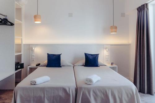 two beds with blue pillows in a room at Hotel Tarba in San Antonio