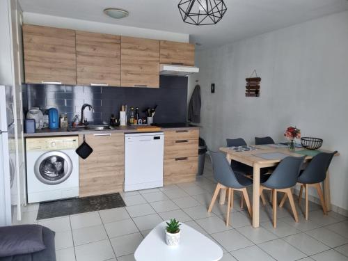 une cuisine avec une table et une machine à laver dans l'établissement Appartement T3 Goélia, à Pierrefiche