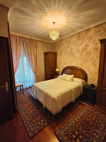 a bedroom with a large bed and a chandelier at Pension Lorea in San Sebastián