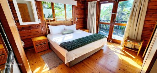 a bedroom with a bed in a room with windows at Milkwood Lodge 5 - Sleeps 6 in Port Edward