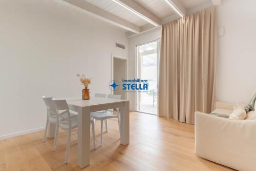 a white dining room with a table and chairs at Wave Island in Lido di Jesolo