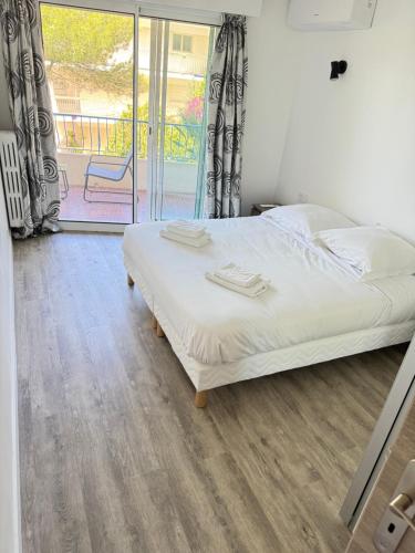 une chambre avec un lit avec des draps blancs et une fenêtre dans l'établissement Appartement vue mer, Long Beach, à Cannes
