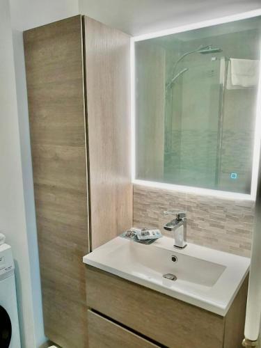 une salle de bain avec un lavabo et un miroir dans l'établissement Appartement vue mer, Long Beach, à Cannes