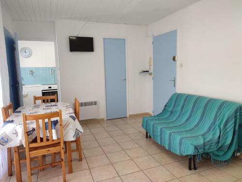 - un salon avec une table et une couverture bleue dans l'établissement T1 dans immeuble sur plage, au Grau-du-Roi