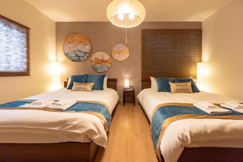 a bedroom with two beds and a chandelier at Tsukiyume Kan - 10m to USJ, Tennoji & KIX Direct, 無料ガレージ付, 和モダン貸切一軒家, ユニバーサルスタジオジャパン近隣 in Osaka