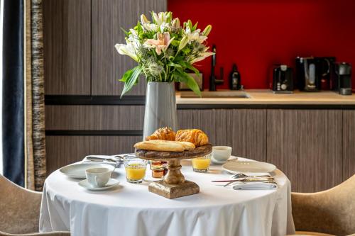 a table with a vase of flowers and croissants at Maison Boissière BARNES Residences in Paris