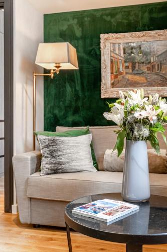 a living room with a couch and a vase of flowers on a table at Maison Boissière BARNES Residences in Paris