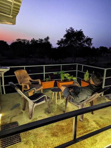 a man laying on a balcony with chairs and tables at Cabana Eden - Cabin in the woods with splash pool in Hyderabad