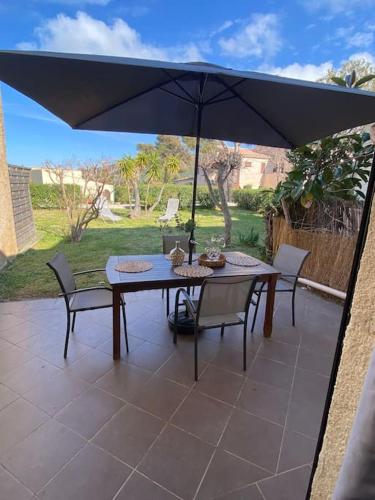 une table et des chaises avec un parasol sur une terrasse dans l'établissement Appart Rez jardin 500 m plage - toutes commodités, à Lumio