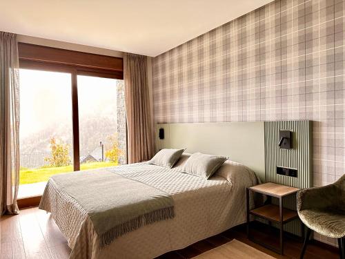 a bedroom with a bed and a large window at BOJ Casas de Montaña in Bielsa