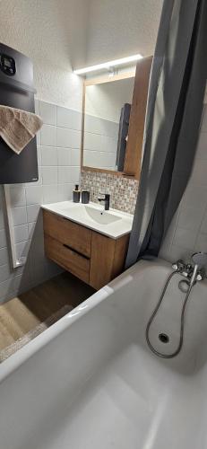 une salle de bain avec une baignoire et un lavabo dans l'établissement Appartement - Métabief, à Métabief