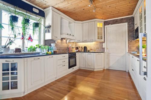 a kitchen with white cabinets and a wooden ceiling at Klara in Sandefjord