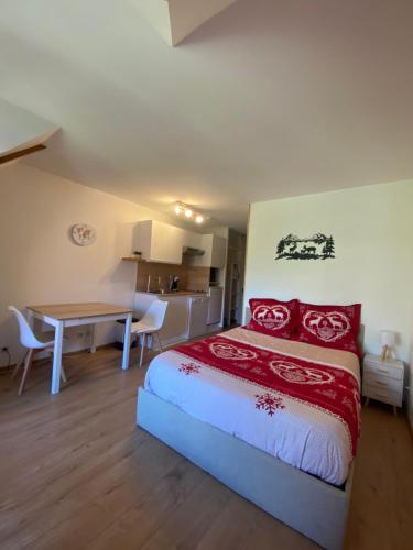 a bedroom with a bed with red pillows and a table at LE NID DU BIRDIE, Giez, Proche du lac d’Annecy in Giez