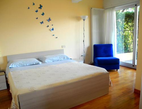a bedroom with a bed with a blue chair and birds on the wall at ColleMare in Pesaro