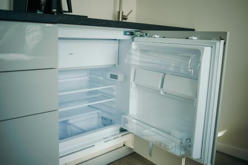 an empty refrigerator with its door open in a kitchen at Taikos apartamentai in Klaipėda