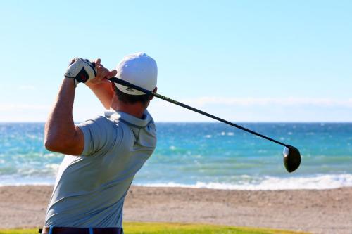 a man swinging a golf club at the beach at Impressive Playa Granada Golf in Motril