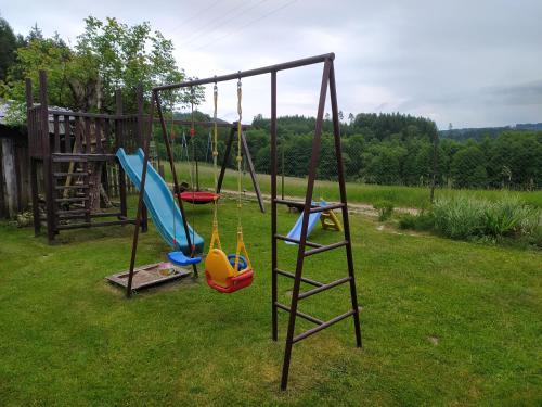 a swing set with three swings in a yard at Apartmán u lesa u Adršpachu in Jívka