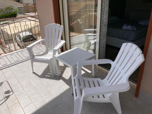 two white chairs and a table on a patio at dalie's house San Leone Centro in Agrigento